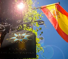 Uithangbord met zonembleem naast een Spaanse vlag