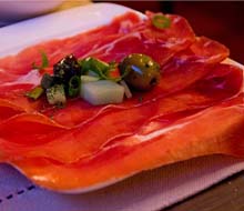 Een bord gedroogde ham met garnituur