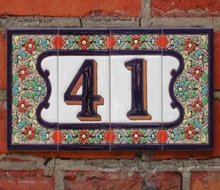 Keramisch huisnummer 41 met kleurrijke bloemenrand op een bakstenen muur